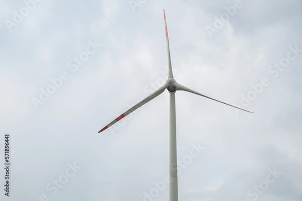 Fototapeta Modern wind turbine renewable energy during daylight with cloudy sky, view from low angle