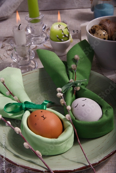 Fototapeta Festive Easter table setting with green napkin Easter Bunny, willow tree branches and easter eggs on green plate.