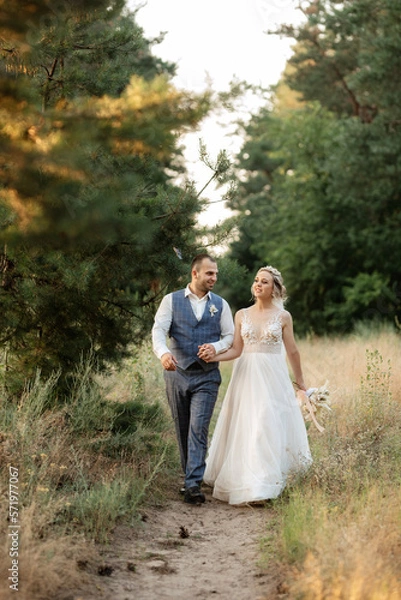 Fototapeta the groom and the bride are walking in the forest