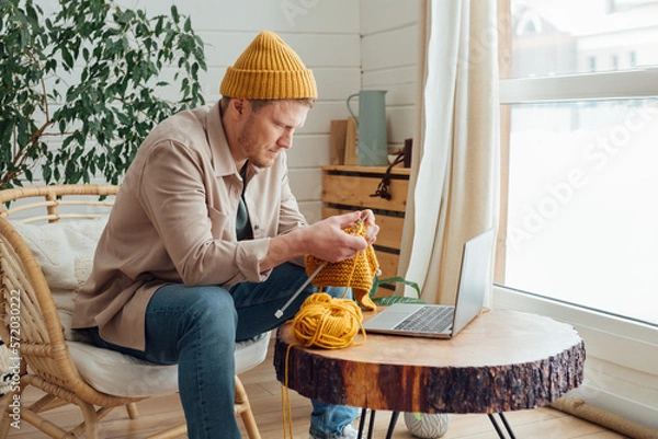Obraz Middle aged man knitting at home. Knitting project in progress. Man learning a new hobby