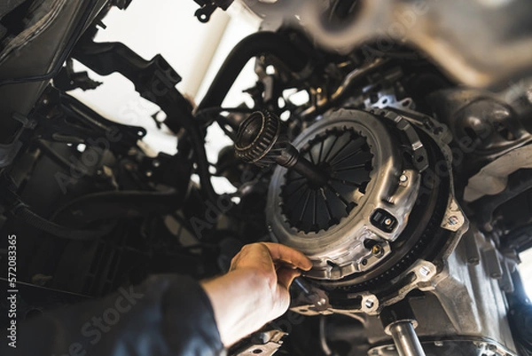 Fototapeta closeup shot of an auto mechanic installing a new clutch kit for a car, auto repair shop. High quality photo