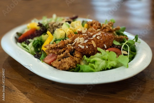 Fototapeta A large vegetable salad with battered fried crab in a white plate on the dining table, eat together to add balance in the body by eating vegetables