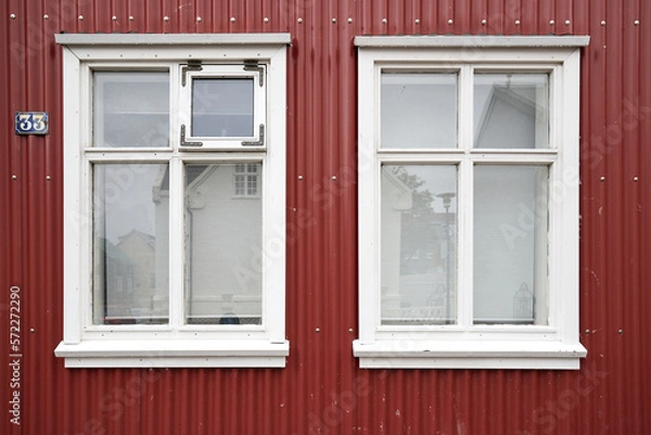 Fototapeta Red house facade with two white windows and red siding, with number 33, Reykjavik, Iceland