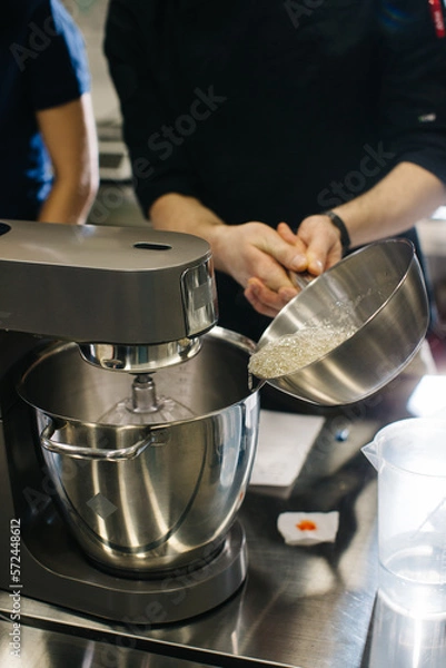 Fototapeta The chef works with a dough mixer. Adding caramel, close-up.