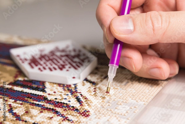 Fototapeta A woman collects a diamond mosaic.The process of creating a picture of multicolored rhinestones