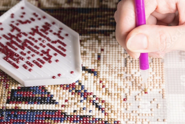 Fototapeta home hobby to draw a picture of rhinestones, multicolored diamond mosaic. the process of gluing a pencil of rhinestones on the canvas of the picture.