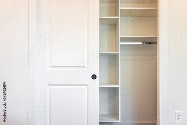 Fototapeta Walk-in closet shelves with sliding door in modern minimalist white style with bright light in staging model house apartment bedroom