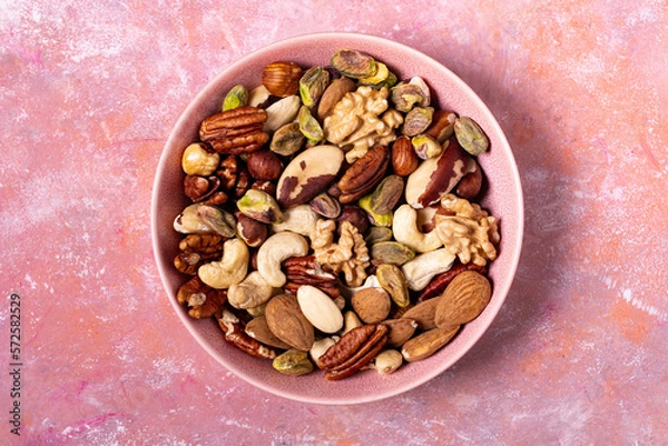 Fototapeta Viewed from above, against a textured background, an isolated bowl holds a large variety of shelled nuts.