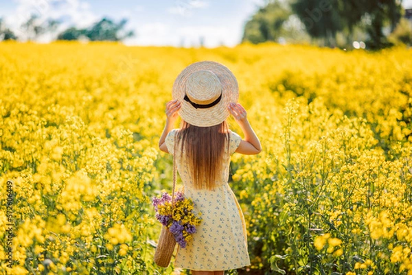 Obraz girl in a hat in a field of yellow flowers, rear view
