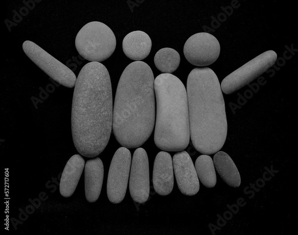 Fototapeta Team of four people. group meeting collaboration. great work. Happy three friends. family embrace together. symbol made from many pebbles. grey stones in the form of kid, father and mother. hands up