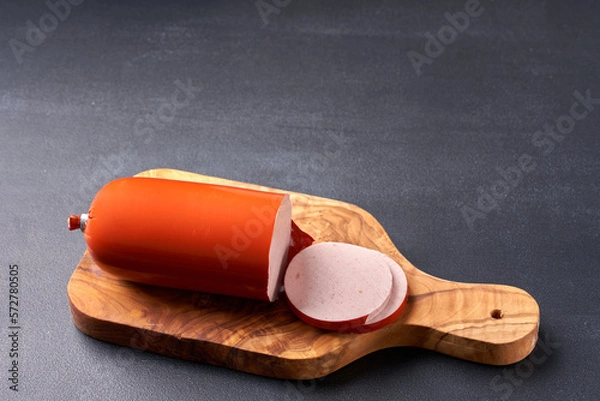 Obraz Boiled ham sausage sliced on a wooden kitchen board.