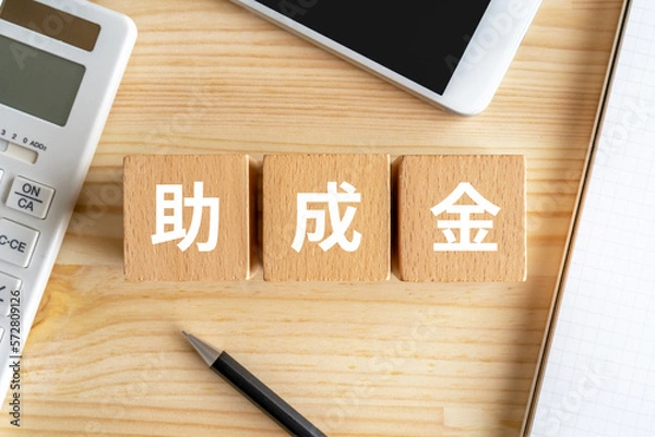 Fototapeta 助成金と書かれたブロック、電卓、スマホ、ノート