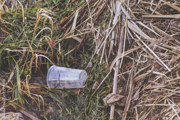 Fototapeta Top view of a plastic glass left on ground. Concept of enviromental issues, ground pollution, ecology problems.