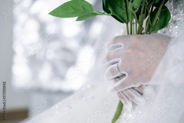 Fototapeta The bride holds flowers in her hands and wears a ring.