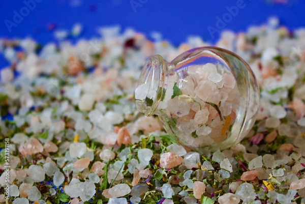Obraz small salt shaker filled with herbal salt on a pile of herbal salt, blue background, close up