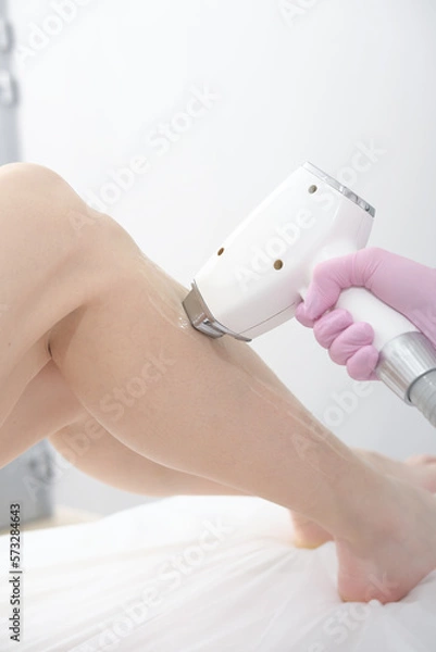Fototapeta laser epilation procedure, beautician touching woman's leg with laser apparatus. skin care, smooth and beautiful legs in salon., vertical
