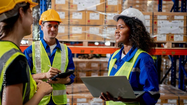 Fototapeta Industrial warehouse diversity engineer or worker man and woman meeting co-working talking together and checking stock goods and box shelf stock in the warehouse factory store. Warehouse Logistic conc