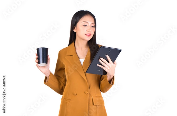 Fototapeta Smiling young woman holding a coffee cup and a tablet, isolated on a white background, perfect for business, technology, and lifestyle-themed projects.