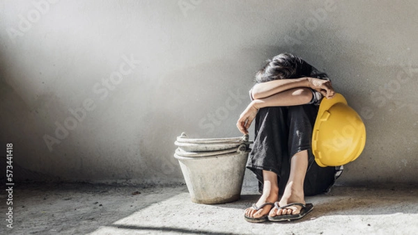 Fototapeta Exhausted little girl sitting on floor concrete wall background. child labor and exploitation