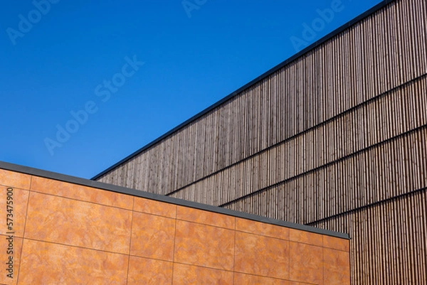 Fototapeta Abstract photo of blue sky, rusty weather resistant steel / corten steel and a wooden wall. Divied into triangles. Anonymous architecture. Vertical shot with copy space.