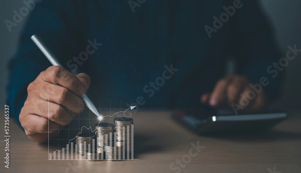 Fototapeta Businessman drawing an increasing graph with coin stacking for increased financial interest rate. Inspiration for business investment, and growth from dividend concept.