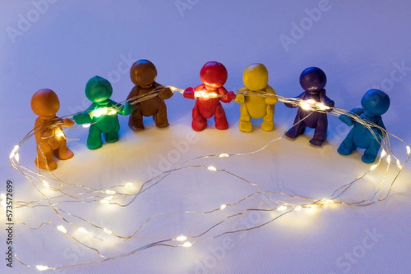 Obraz Figuren aus Knete halten eine Lichterkette, symbolische Darstellung für Zusammenhalt. 
