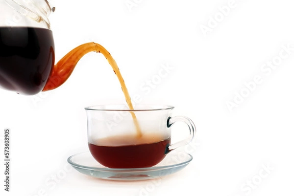 Obraz Fragrant black tea is poured from a teapot into a glass cup. White background.