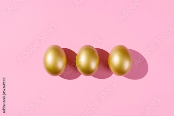 Fototapeta Easter template with golden eggs. Egg painted gold on pink background. Easter concept with copy space for text. Flat lay style minimalistic design.