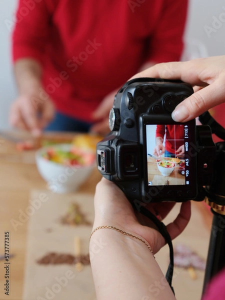 Fototapeta Photography studio shooting cooking blog content. Photo camera on tripod shooting how man is cooking
