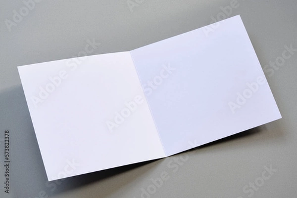 Fototapeta Laying blank open empty square greeting card mock up on grey background. For use as a Christmas, birthday, wedding or celebration background template.	

