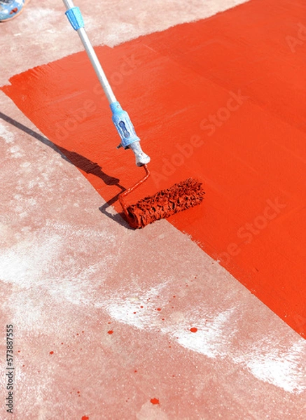 Obraz Worker waterproofing the terrace of the building with red rubber waterproofing paint spread with a roller