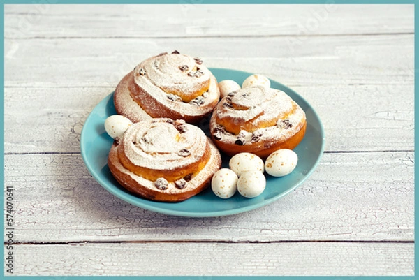 Fototapeta Delicious fresh pastries with icing sugar on a blue plate with chocolate sweet eggs for Easter gift