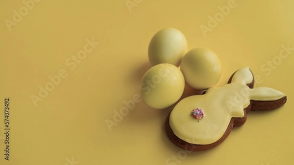 Fototapeta Three yellow eggs and rabbit cookies for Easter celebration
