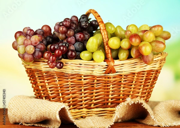 Fototapeta Fresh grape on wicker mat on bright background