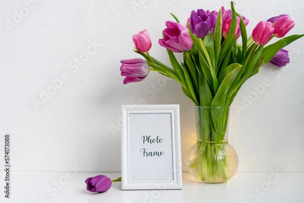 Fototapeta  white frame mock up and dry twigs in vase on book shelf or desk. White colors. 