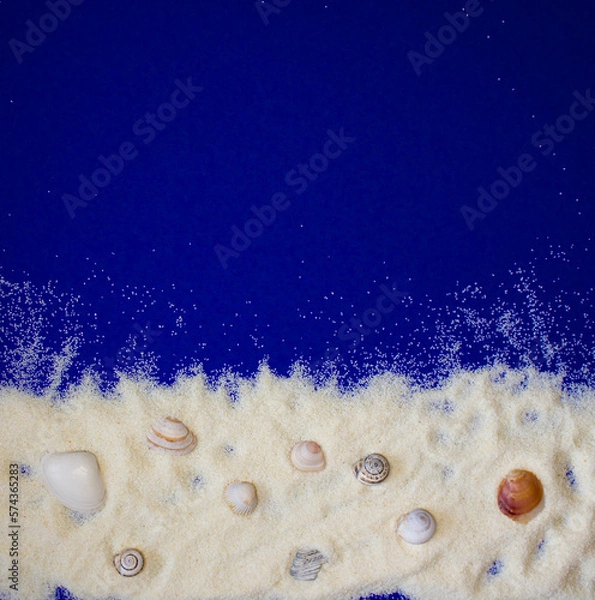 Obraz frame made of sand, shells and snail shells on a dark blue background on which to write or present something, top view