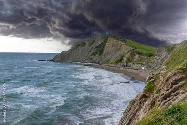 Obraz  The storm is approaching on the green grassy ridges forming Flysch on the rocks on a summer day in Zumaia. Basque. Spain