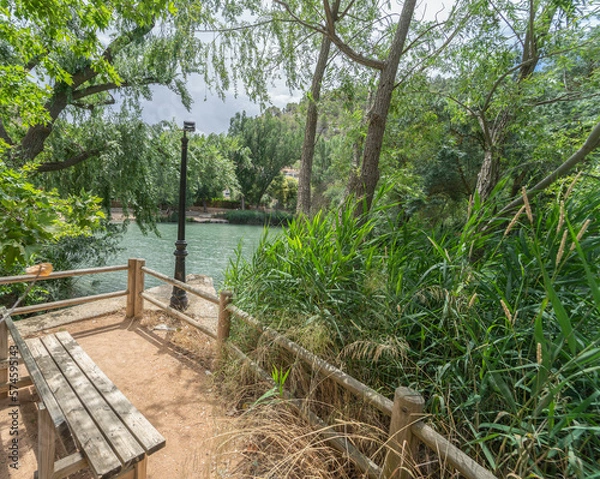 Obraz Bench in the recreational area of Alcala del Jucar, overlooking the green and dense vegetation of the Jucar river.