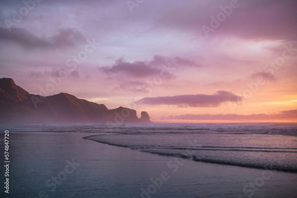 Obraz Purple skies and gentle waves at Piha Beach, New Zealand.