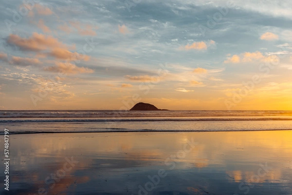 Obraz The warm glow of a setting sun reflects on the glassy Maukatia Bay beach, painting it a soft orange and pink hue.