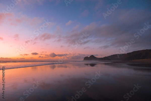 Obraz A stunning view of Bethells Beach, captured at sunset, with vibrant tones of pink, violet, and orange filling the sky.