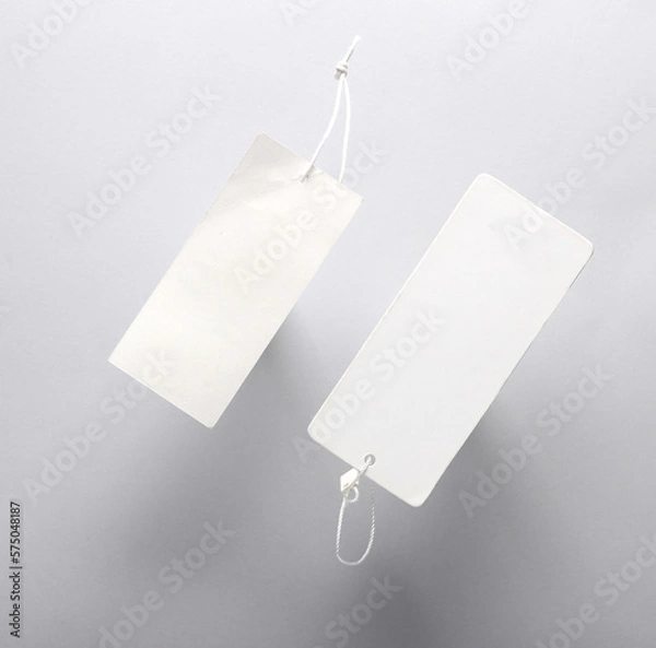 Fototapeta White Blank clothing price tags or labels mockup with strings on gray background. Sale, shopping concept. Top view
