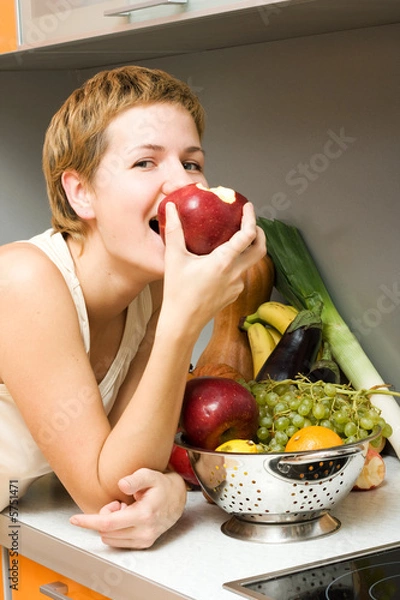 Fototapeta Beautiful girl eating fresh fruits at the kitchen