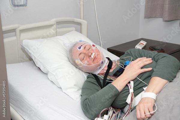 Fototapeta Middle aged woman measuring brain waves, examining polysomnography in sleep lab