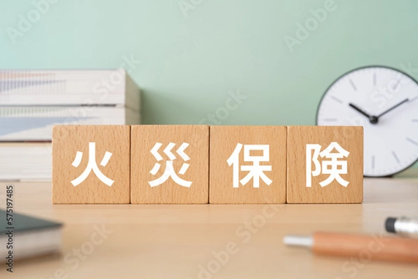 Obraz 火災保険と書かれたブロックが置かれたデスク
