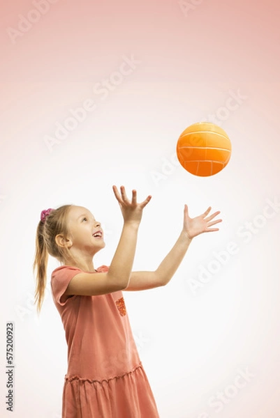 Obraz A cute happy girl throwing a ball.