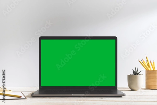 Fototapeta Chroma key green screen laptop on table with white background.