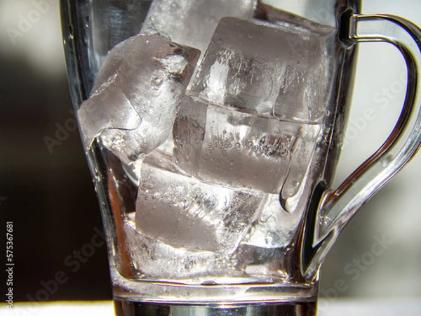 Fototapeta a glass with ice cubes in it sitting on a table