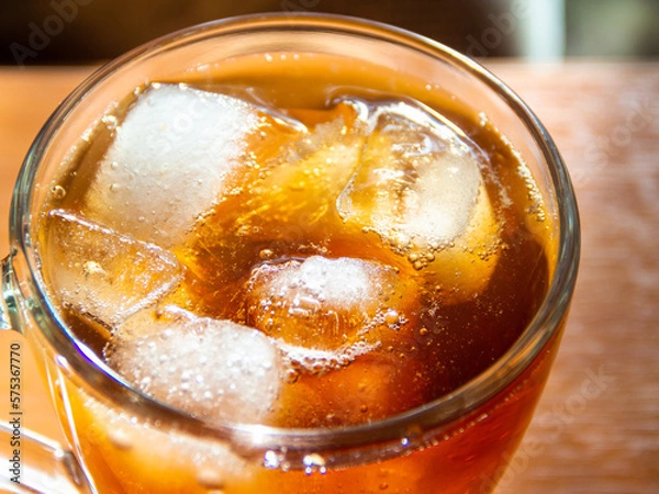 Fototapeta a glass of soda with ice on a wooden table