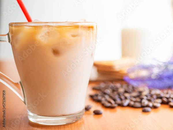 Fototapeta Ice coffee in a glass with milk with coffee beans on the table.Cookies and milk bottle.